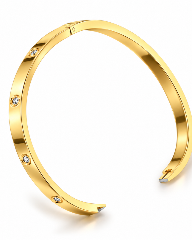 A polished gold-tone open cuff bracelet with four small clear gemstones set along the front, shown on a clean white background.